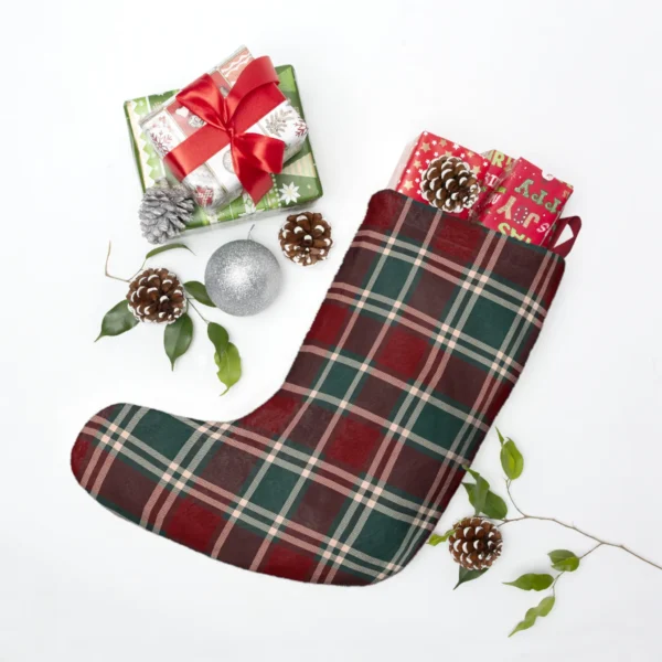 Burgundy plaid stocking laid flat beside wrapped presents, pine cones, a silver bauble and green sprigs