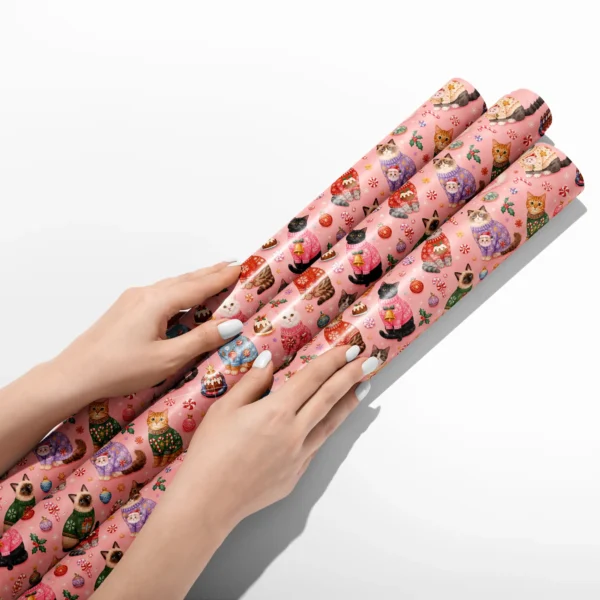 Hands smoothing three rolls of Christmas cat wrapping paper on a white table