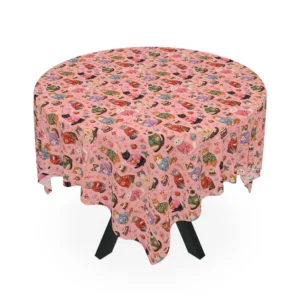 Pink tablecloth on a round table printed with cats in colorful holiday sweaters, candy canes and puddings