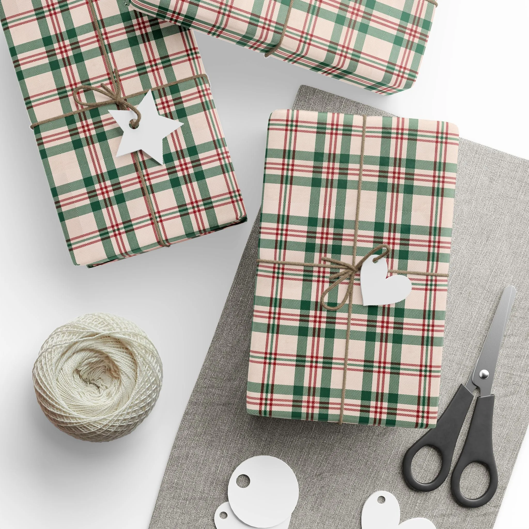 Presents wrapped in cream, green and red plaid wrapping paper with twine, paper tags, scissors and a ball of string