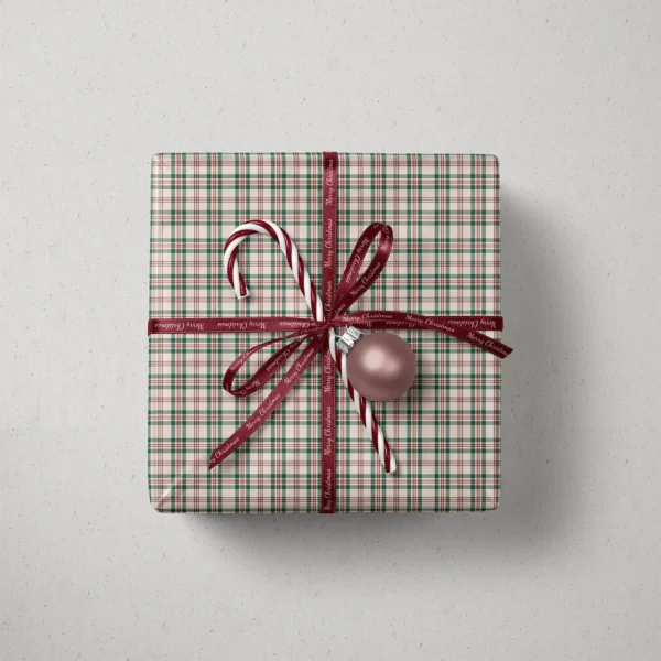 Top view of a gift in cream plaid paper with a ribbon, candy canes and a bauble