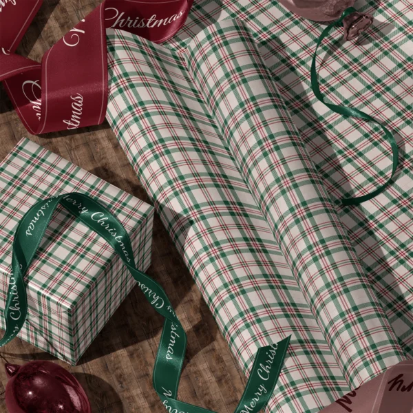 Rolls of cream plaid gift wrap and a wrapped box with satin ribbons on a wooden floor