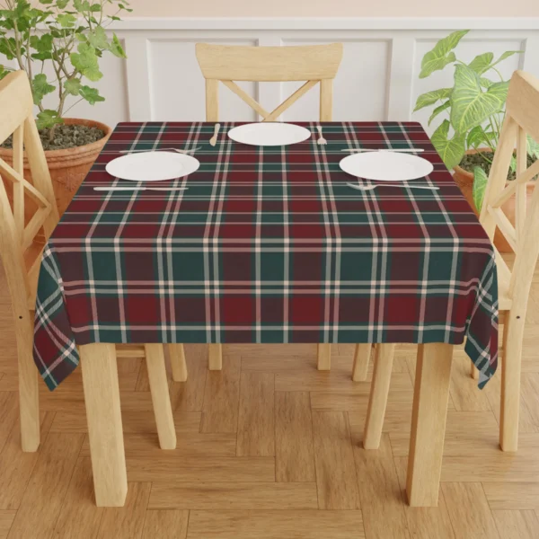 Burgundy check tablecloth on a dining table set with three white plates between wooden chairs