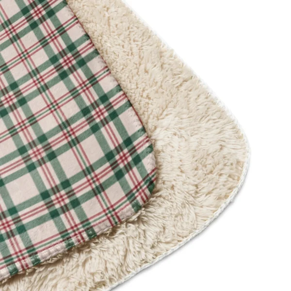 Close-up of a rounded blanket corner showing the green and red check against thick fluffy sherpa