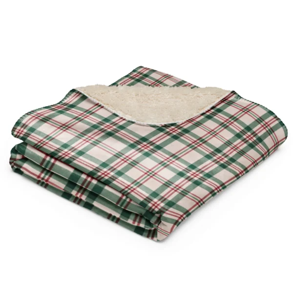Folded plaid Christmas blanket with one corner turned back to show the fluffy light tan sherpa side