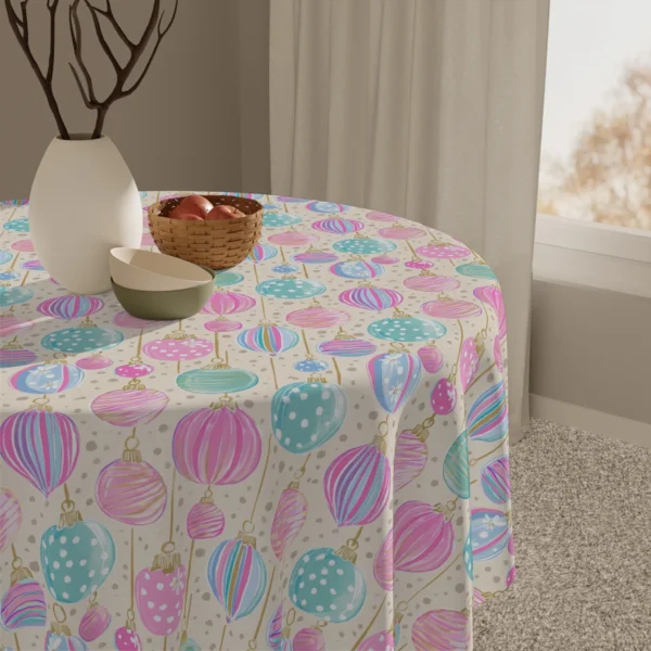 Detail of striped and dotted pastel baubles on cream fabric beside a white vase and a basket of apples