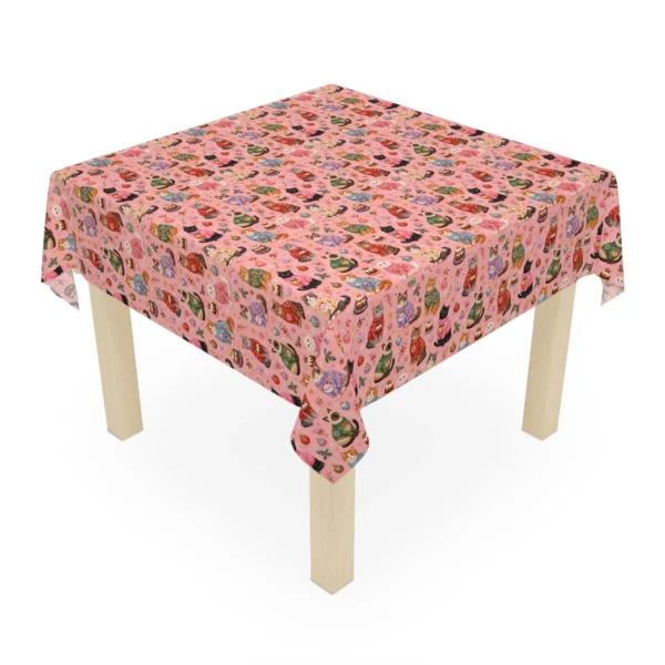 Square table covered in a pink Christmas cloth full of little cats in knitted jumpers