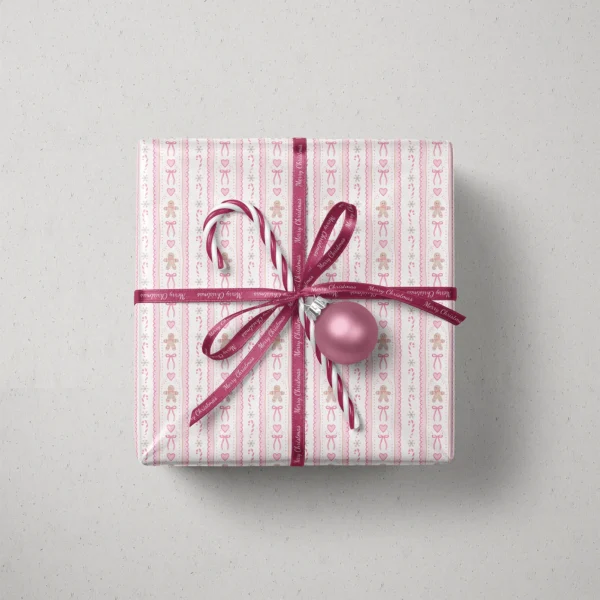 Top view of a gift in pink gingerbread paper with a ribbon, candy canes and a bauble