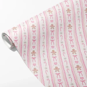 Roll of cream wrapping paper with pink scalloped stripes, gingerbread men and bows, partly unrolled on white