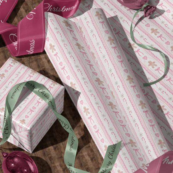 Rolls of pink gingerbread gift wrap and a wrapped box with satin ribbons on a wooden floor