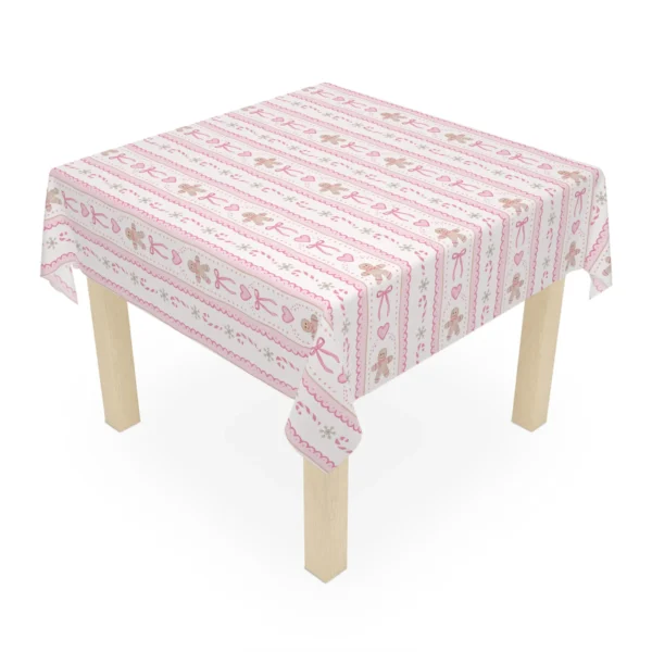 Small square wooden table covered by a cream and pink gingerbread Christmas tablecloth