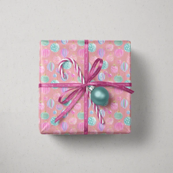 Top view of a gift in pink pastel ornament paper with a ribbon, candy canes and a bauble