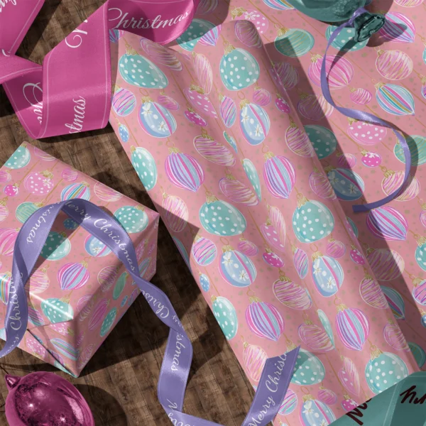 Rolls of pink pastel ornament gift wrap and a wrapped box with satin ribbons on a wooden floor