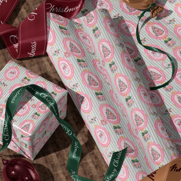 Rolls of pink Santa sage stripe gift wrap and a wrapped box with satin ribbons on a wooden floor