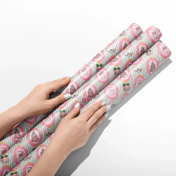 Hands smoothing three rolls of pink Santa sage stripe wrapping paper on a white table