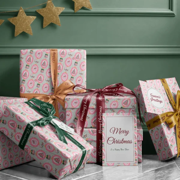 Stack of presents in pink Santa sage stripe paper with ribbons and a Merry Christmas card by a green wall
