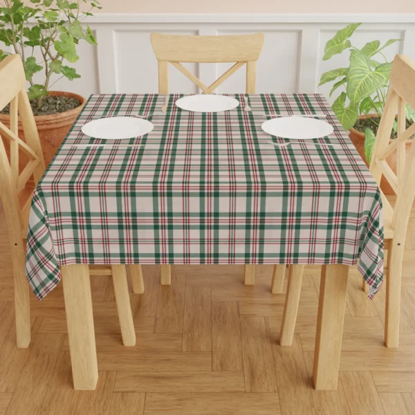 Cream, green and red plaid tablecloth on a square wooden table set with white plates, chairs around it
