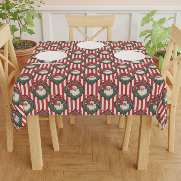Dining table set with white plates on a red and cream Santa tablecloth between wooden chairs