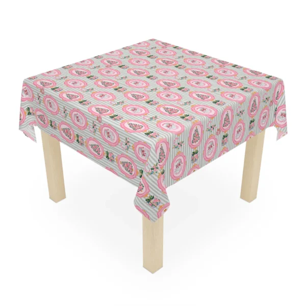 Square wooden table covered by a pastel Christmas tablecloth with pink medallions on sage and white stripes