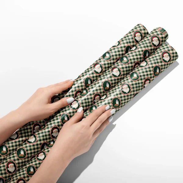 Hands smoothing three rolls of Santa milk and cookies gingham wrapping paper on a white table