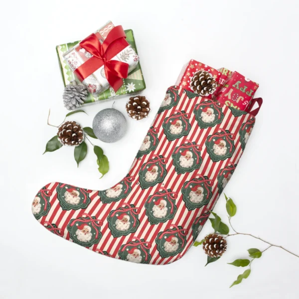Striped vintage Santa stocking laid flat beside wrapped presents, pine cones and a silver ornament