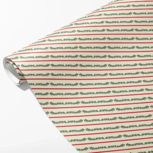 Roll of cream wrapping paper with thin red lines alternating with green berry garlands, partly unrolled on white