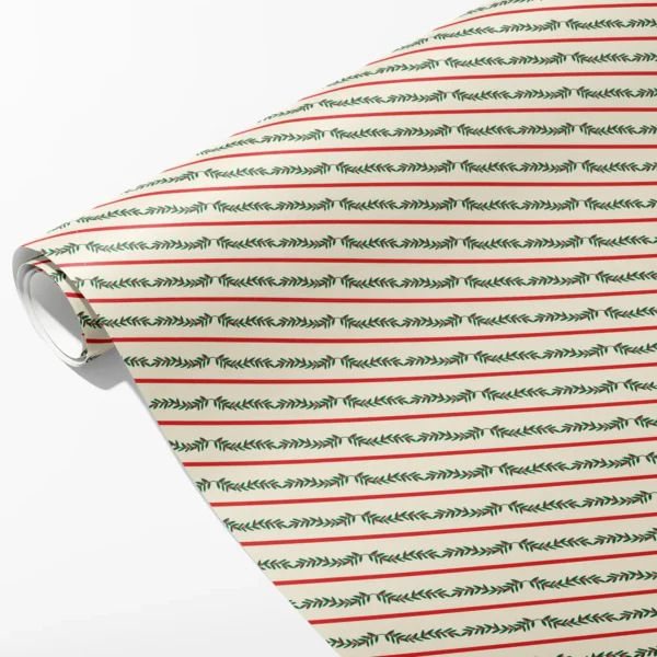Roll of cream wrapping paper with thin red lines alternating with green berry garlands, partly unrolled on white