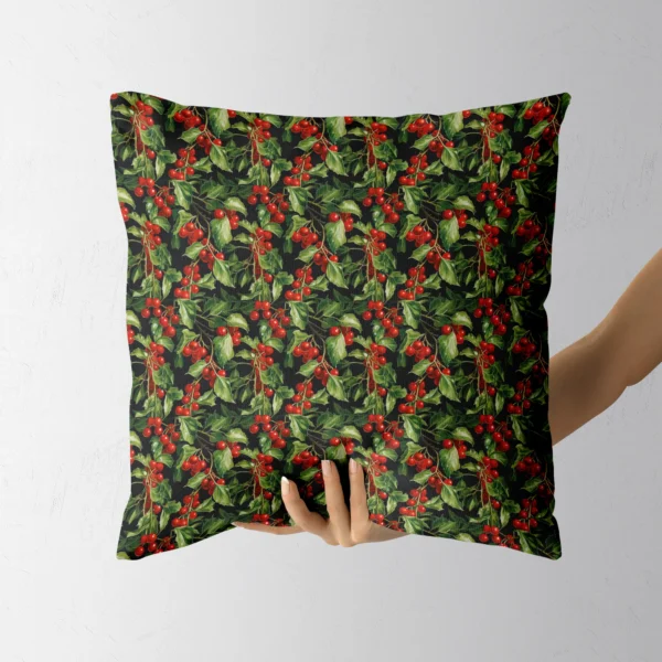 Hand holding the square black pillow with red holly berries