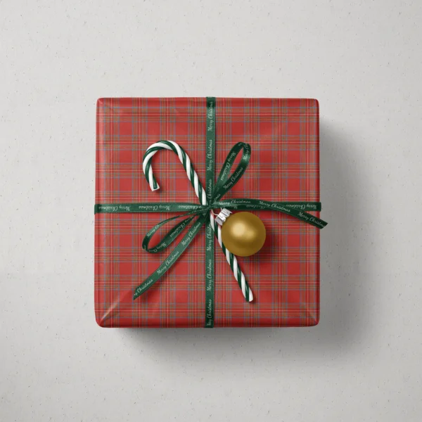 Top view of a gift in red tartan paper with a ribbon, candy canes and a bauble