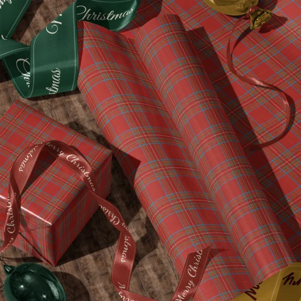Rolls of red tartan gift wrap and a wrapped box with satin ribbons on a wooden floor