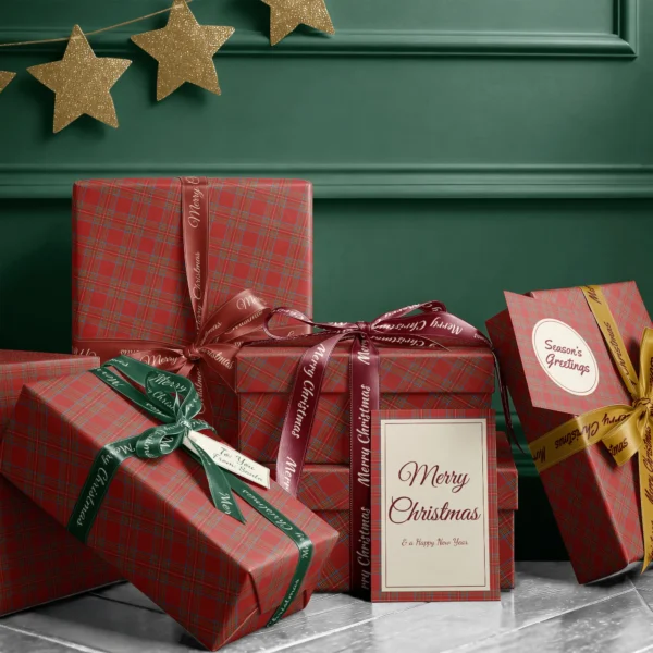 Stack of presents in red tartan paper with ribbons and a Merry Christmas card by a dark green wall