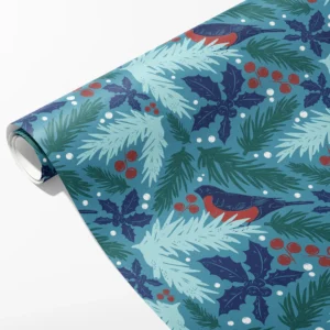 Roll of teal wrapping paper with red-breasted bullfinches, pine boughs, navy holly and red berries, partly unrolled on white
