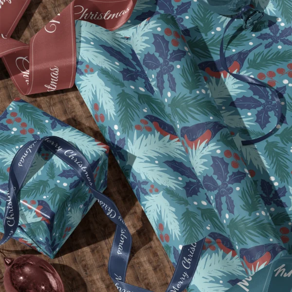A sheet of teal bullfinch gift wrap and a wrapped box with satin ribbons on a wooden floor