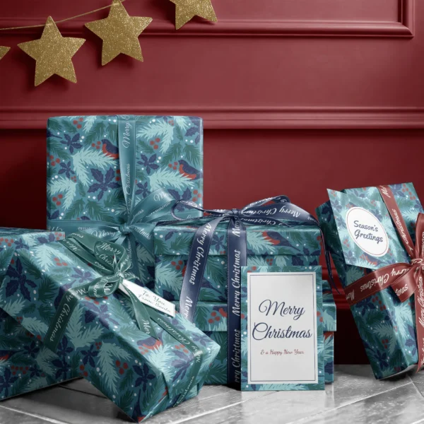 Stack of presents in teal bullfinch paper with ribbons and a Merry Christmas card by a burgundy wall
