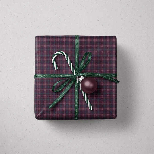 Top view of a gift in burgundy houndstooth plaid paper with a ribbon, striped candy and a bauble