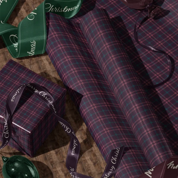 Rolls of burgundy houndstooth plaid gift wrap and a wrapped box with satin ribbons on a wooden floor