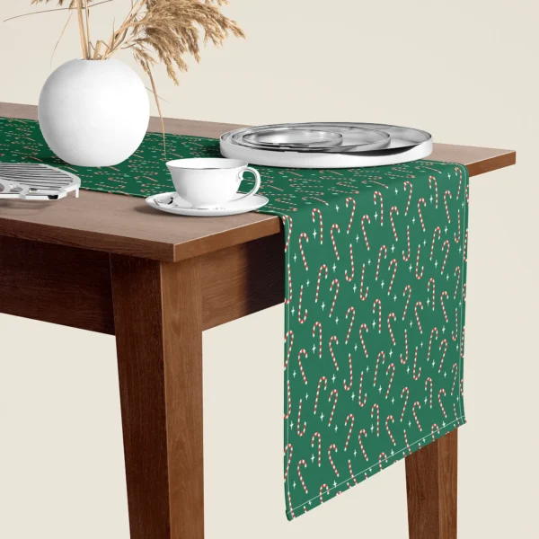 Candy cane Christmas table runner hanging over the end of a walnut dining table, close-up