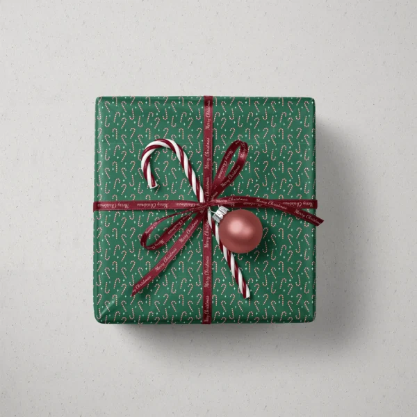 Top view of a gift in candy cane paper with a ribbon, candy canes and a bauble