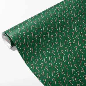 Roll of green wrapping paper with small red and cream candy canes and cream stars at angles, partly unrolled on white