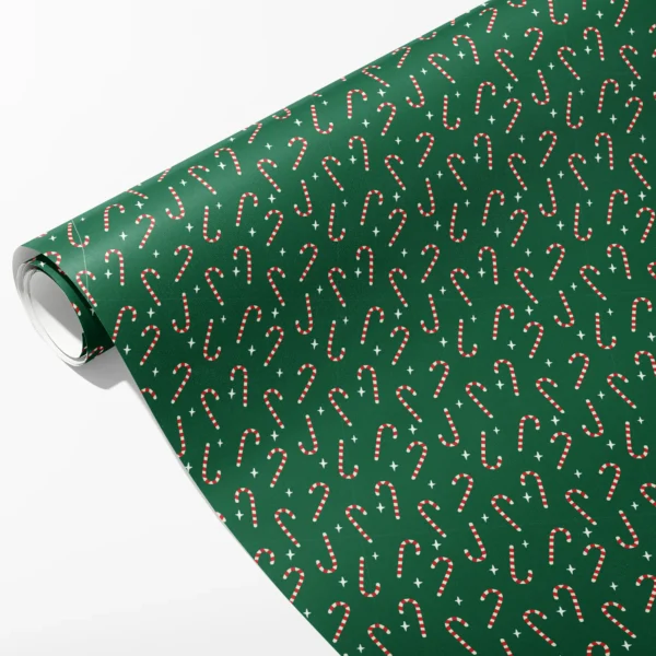 Roll of green wrapping paper with small red and cream candy canes and cream stars at angles, partly unrolled on white