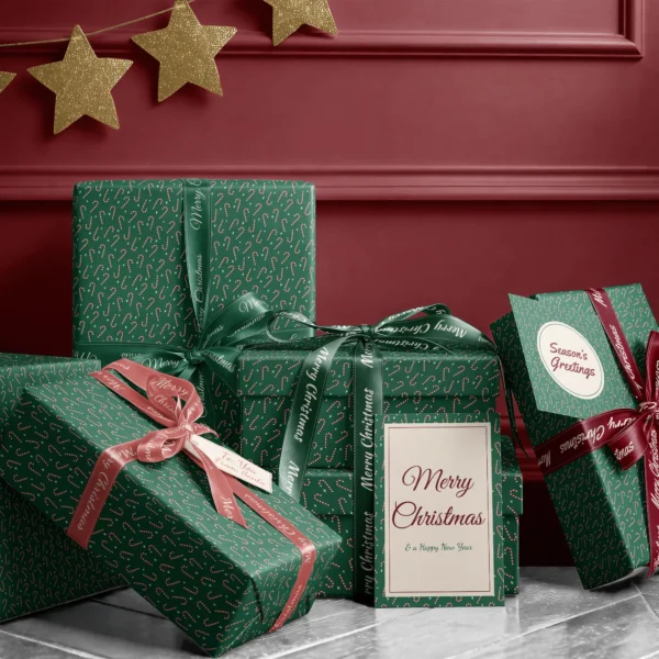 Stack of presents in candy cane paper with ribbons and a Merry Christmas card by a burgundy wall