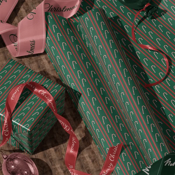 Rolls of candy cane stripe gift wrap and a wrapped box with satin ribbons on a wooden floor