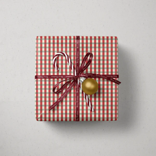 Top view of a gift in candy stripe plaid paper with a ribbon, candy canes and a bauble