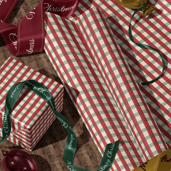 Rolls of candy stripe plaid gift wrap and a wrapped box with satin ribbons on a wooden floor