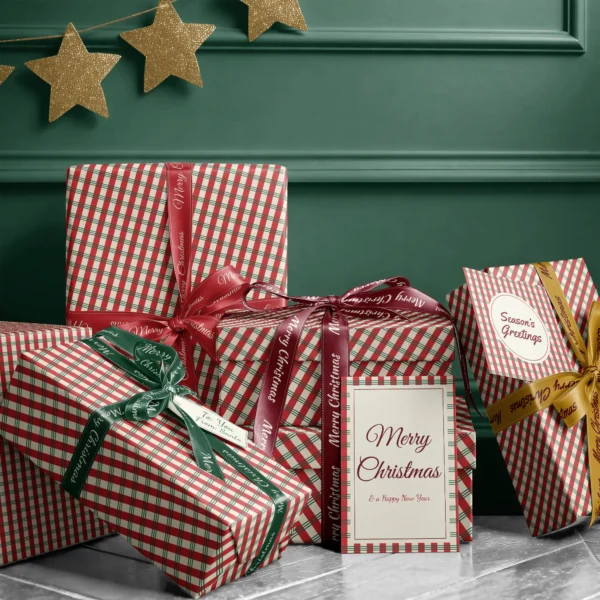 Stack of presents in candy stripe plaid paper with ribbons and a Merry Christmas card by a dark green wall