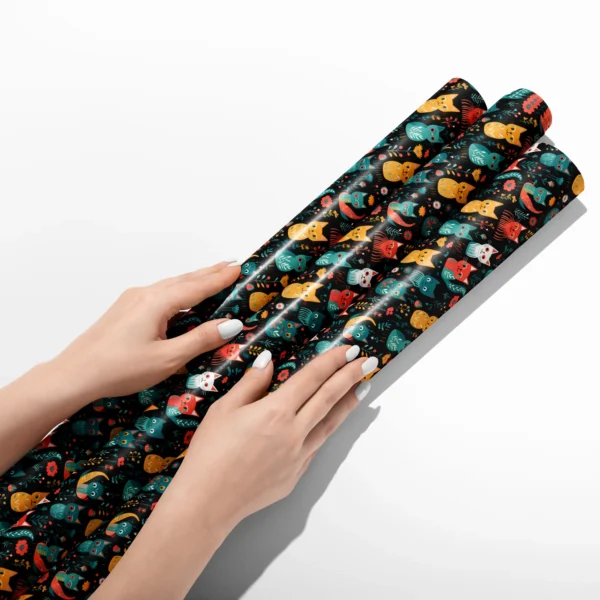 Hands smoothing three rolls of black folk cat wrapping paper on a white table