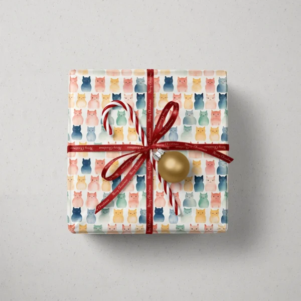 Top view of a gift in cream watercolor cat paper with a red ribbon, a candy cane and a gold bauble