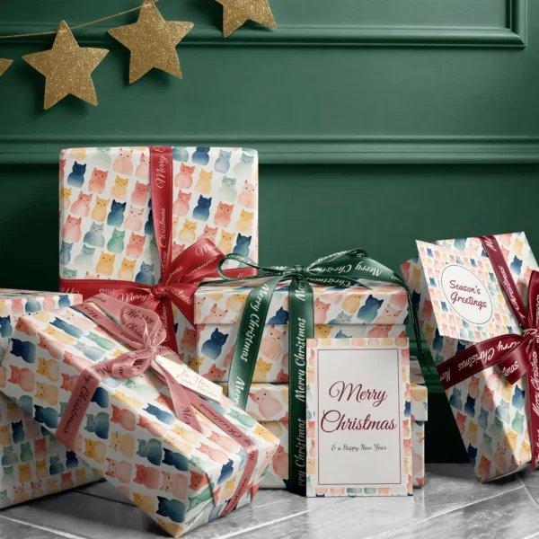 Stack of presents in cream watercolor cat paper with ribbons and a Merry Christmas card by a dark green wall
