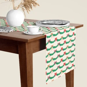 Pine garland and red bow Christmas table runner hanging over the end of a walnut dining table, close-up
