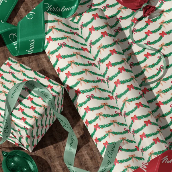 Rolls of pine garland gift wrap and a wrapped box with satin ribbons on a wooden floor